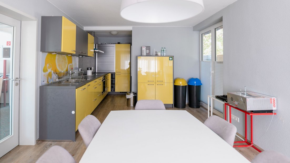 灰黄色的现代小厨房，前景为餐桌组
